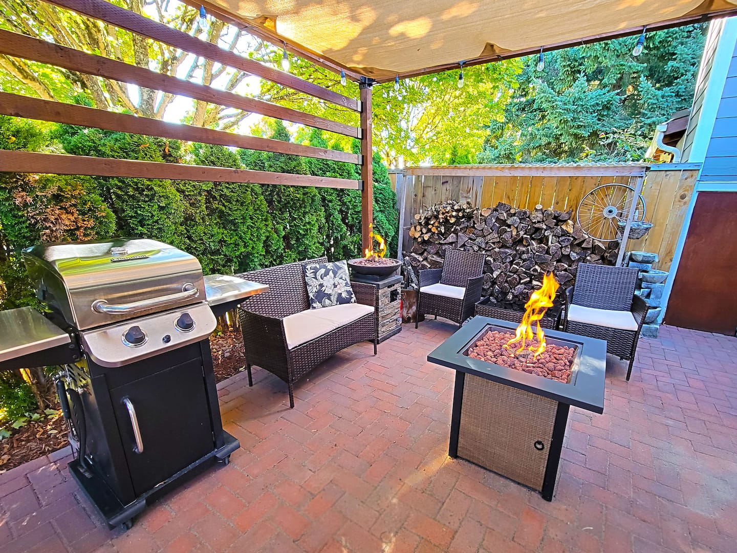 Outdoor covered patio features a standing drink cooler, a BBQ propane grill, and 2 propane firepits, 1 of which converts into a table.